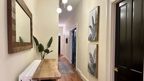 A hallway with a wooden table, a radiator, and artwork on the walls.
