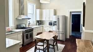 A modern kitchen with white cabinets, stainless steel appliances, and a wooden dining table.