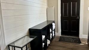 A hallway with a black door, a glass display case, and a black shelf with folded towels.