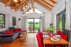 Una sala de estar moderna con un sofá, una mesa de comedor y ventanas amplias.