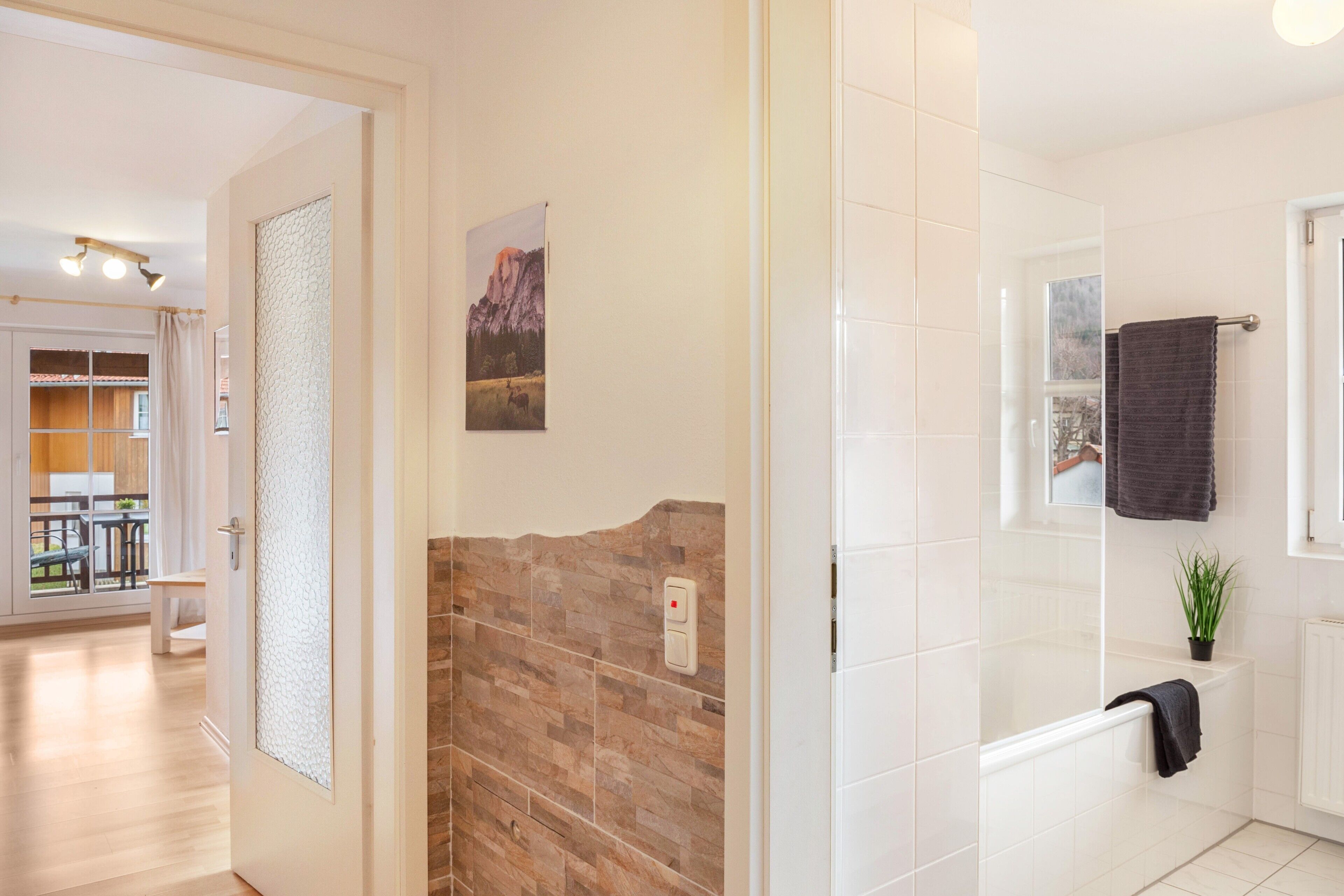 A bathroom with a shower, a towel rack, and a potted plant.