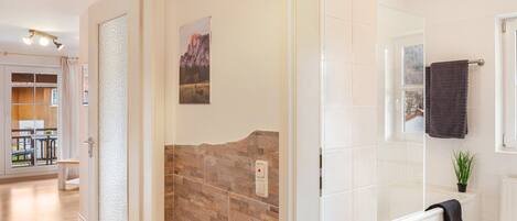 A bathroom with a shower, a towel rack, and a potted plant.