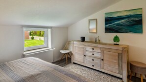 A bedroom with a bed, a dresser, a window, and a painting. - Holiday Home 'Krummes Häusschen An Der Nordsee' with Terrace and Garden (Großheide)