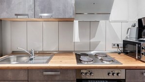 Une cuisine moderne dotée d’un évier en acier inoxydable, d’un plan de travail en bois, d’un four encastré et d’un four à micro-ondes.