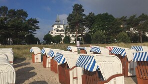 Beach chairs with striped canopies, a sandy beach, and a building with a tower in the background.