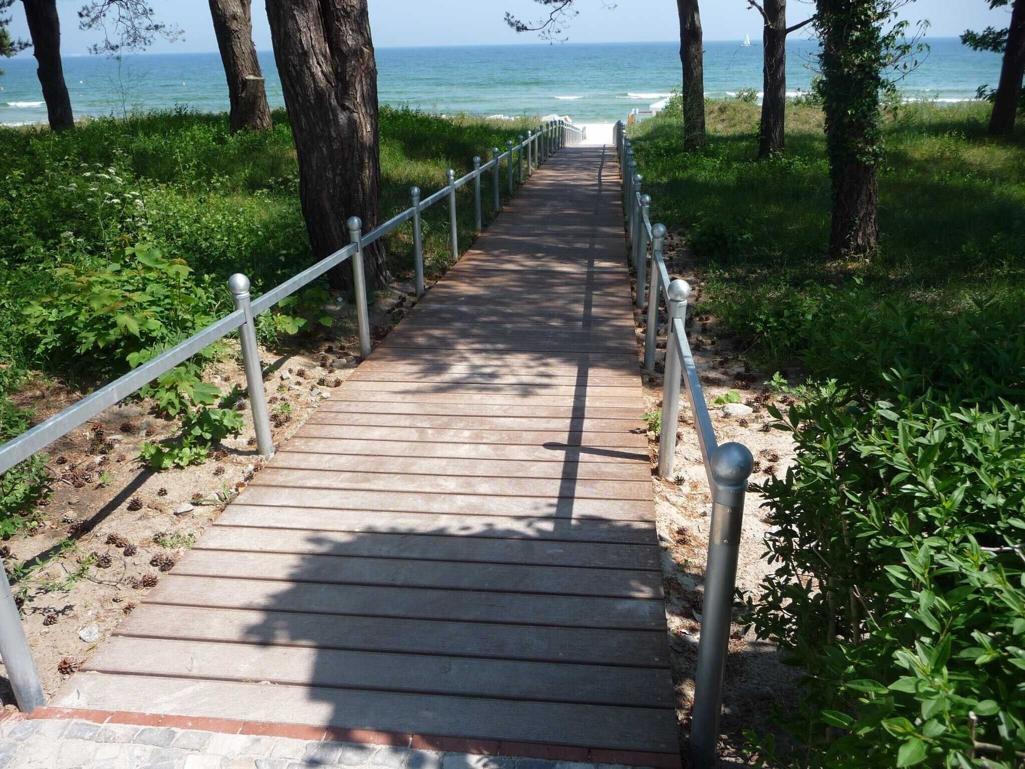 A wooden pathway leading to a beach with metal railings.