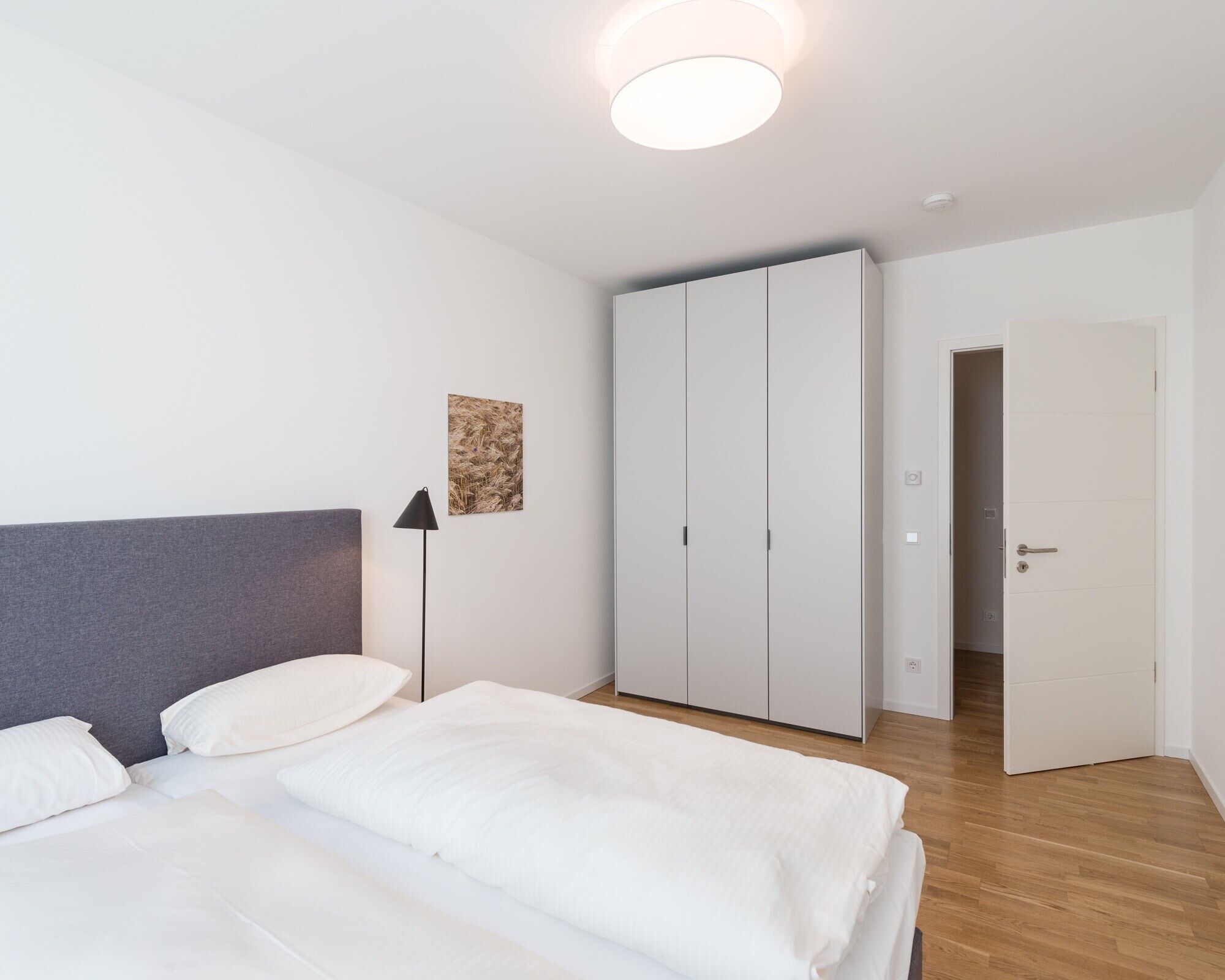 A bedroom with a bed, a wardrobe, and a door leading to another room.