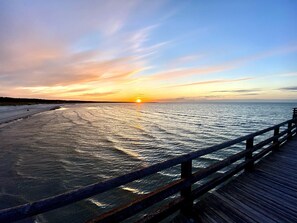 A wooden pier extending into calm waters during sunset.