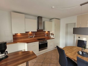 A modern kitchen with white cabinets, a wooden countertop, and a built-in oven. - Friedhoff Apartment, 80 sqm with Mountain View, Private Terrace and Wi-Fi (Schmallenberg)