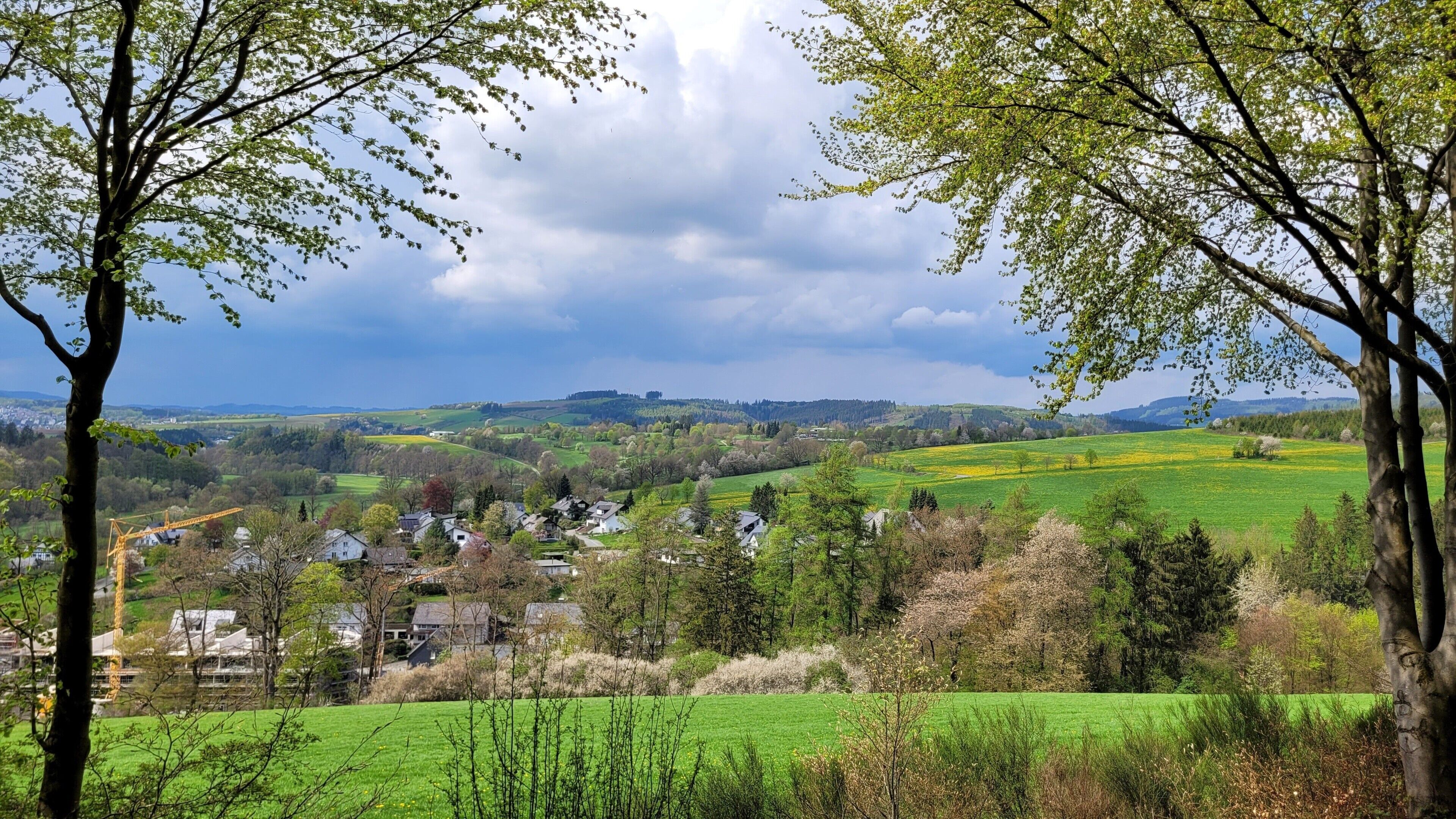A rural landscape with houses, fields, and a cloudy sky.