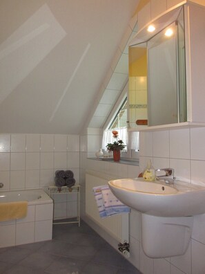 Une salle de bain avec un lavabo blanc, un miroir, un porte-serviettes et un radiateur.