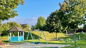 Un'area giochi con altalene, un piccolo padiglione e un tavolo da picnic.