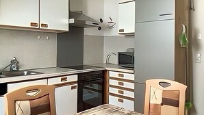 Una cucina compatta con mobili bianchi, un forno a microonde ed una lavastoviglie.