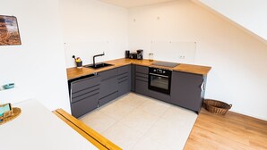 A compact kitchen with a sink, stove, and dark cabinetry. - Apartment 'Ferienwohnung Weitblick Koblenz' with Balcony and Wi-Fi (Koblenz)