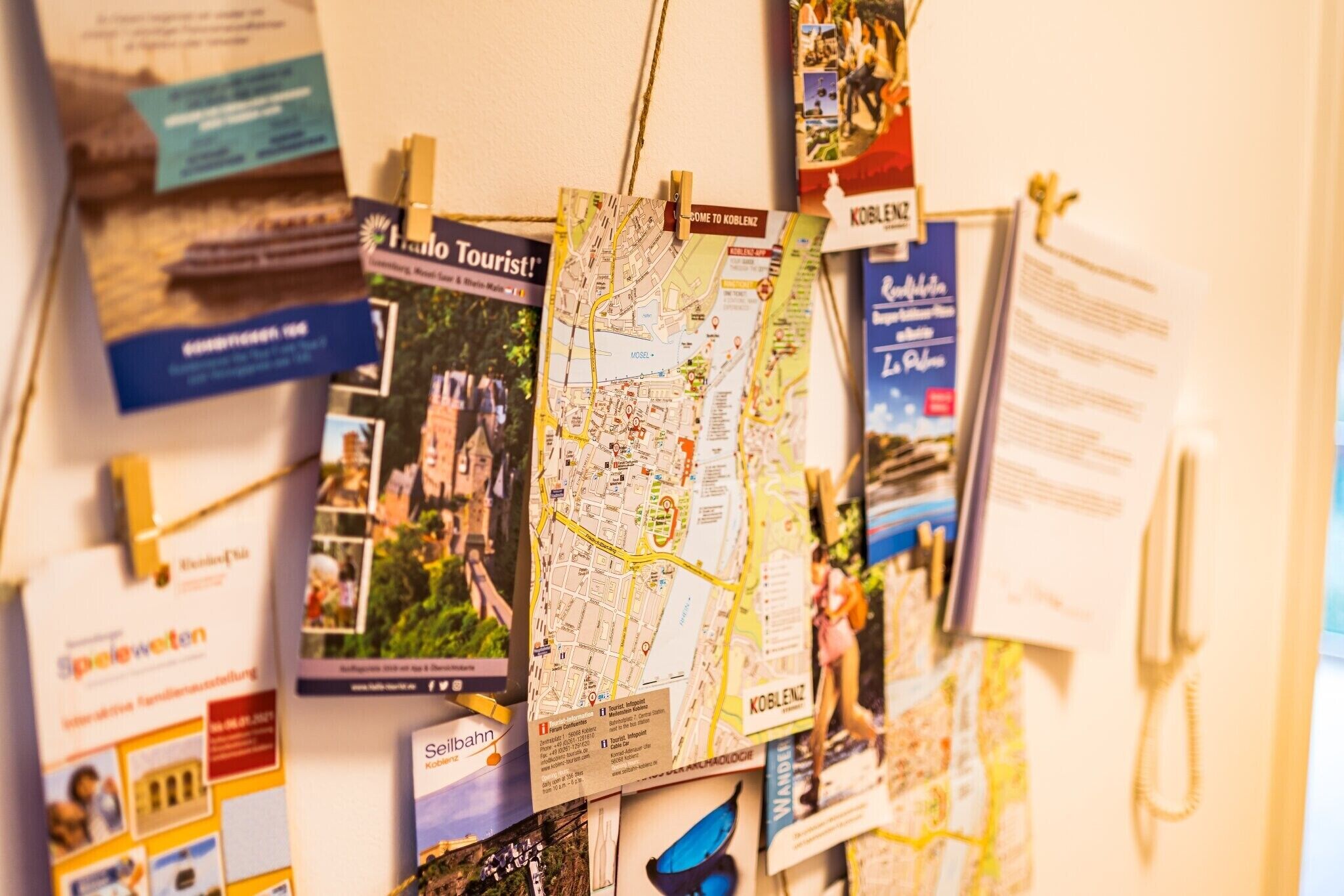 Un mur orné de diverses brochures de voyage, une carte et un téléphone.