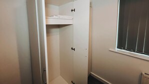 A narrow hallway with a white door, a window with blinds, and a small shelf with folded towels. - Oldbury Heritage Hideaway 02! (Oldbury)