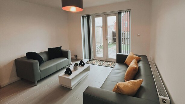 A modern living room with a grey sofa, a black sofa, and a white coffee table. There is a large window with a view of the outside. - Oldbury Heritage Hideaway 02! (Oldbury)