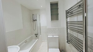 A modern bathroom with a bathtub, toilet, and a glass-enclosed shower area. - Oldbury Heritage Hideaway 02! (Oldbury)