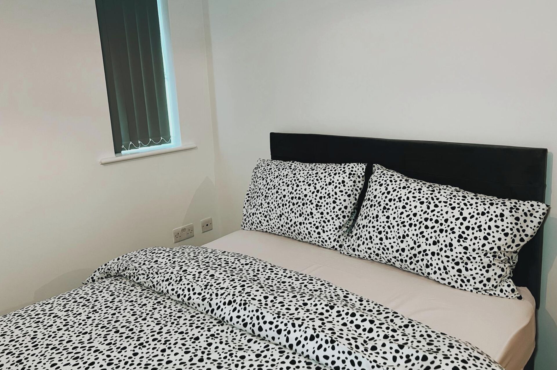 Ein Schlafzimmer mit einem Bett, einem Fenster und einer Steckdose.