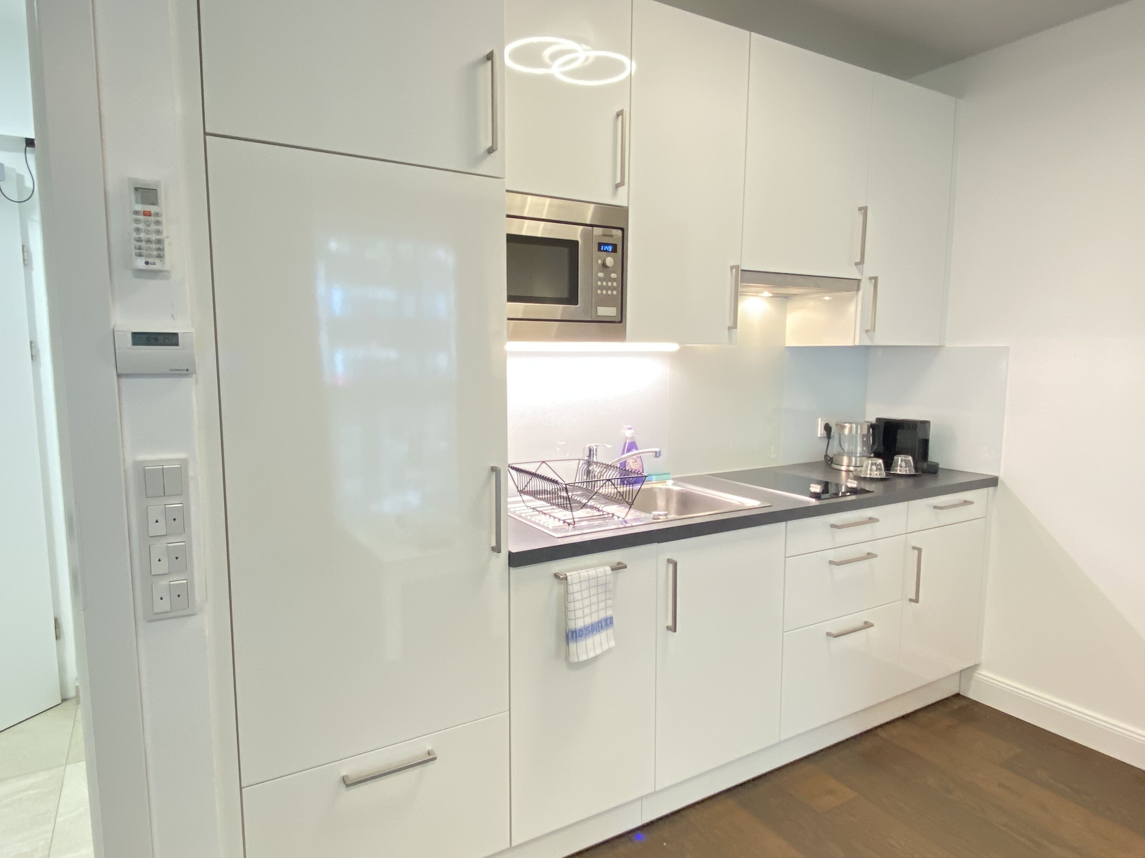A modern kitchen with white cabinets, a built-in microwave, and a stainless steel sink.