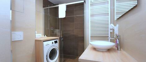 A modern bathroom with a washing machine, toilet, and sink.