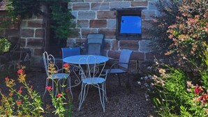 Una casa de piedra con un pequeño balcón, una ventana y una mesa con sillas afuera.