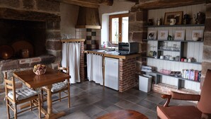 Una cocina rústica con chimenea de piedra, una mesa de madera y un horno empotrado.