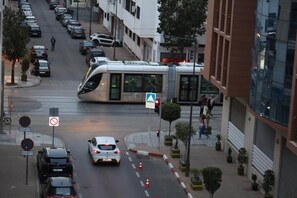 Una calle con coches estacionados, un tranvía y un paso de peatones.