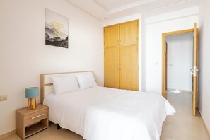 Un dormitorio con cama, armario de madera y mesita de noche con lámpara.