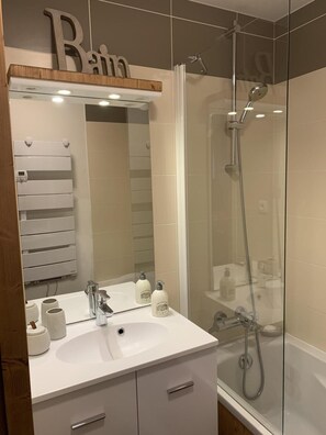 A bathroom with a white sink, mirror, and a shower area. - 4th floor, swimming pool, sauna, hammam, balcony, parking, tv, ski locker, 32m² (Pralognan-la-Vanoise)