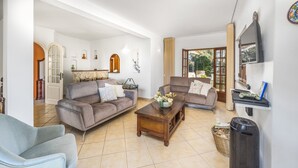 Un salon spacieux comprenant un ensemble de canapés, une table basse et un téléviseur fixé au mur.