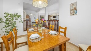 Un espace repas avec une table en bois, dressée pour quatre personnes, entourée de chaises.