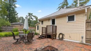 Une terrasse avec un sol en briques, du mobilier d’extérieur et un foyer.