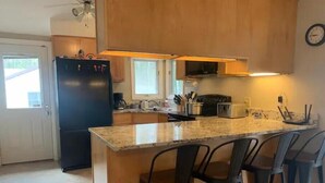 Une cuisine dotée d’un îlot central, de tabourets de bar, d’un réfrigérateur et d’un four à micro-ondes.
