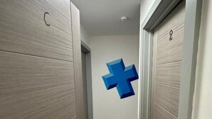 A hallway with wooden doors, a blue cross wall decal, and a number '2' on one door.