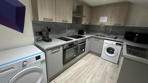 A modern kitchen with built-in appliances, including a washing machine, oven, and microwave.