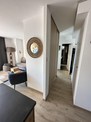 A modern living room with a sofa, a coffee table, and a lamp. There is a hallway leading to another room. - Ground floor, terrace, fireplace or stove, ski locker, 46m², Villard de Lans (Villard-de-Lans)
