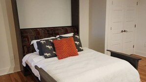 A bedroom with a dark wood bed frame, white bedding, and a large mirror above the bed. - *Downtown Middlebury Waterfall Studio Apartment* (Middlebury)