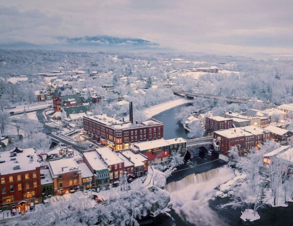 A snow-covered town with buildings, a river, and a waterfall.