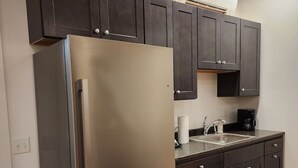 A modern kitchen with dark cabinets, stainless steel appliances, and a wooden floor. - *Downtown Middlebury Waterfall Studio Apartment* (Middlebury)