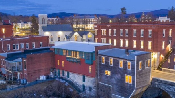 A historic town with a river, buildings with traditional architecture, and a waterfall. - *Downtown Middlebury Waterfall Studio Apartment* (Middlebury)