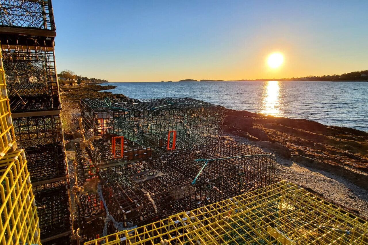 Eine Küstenbaustelle mit Metallgittern und Gerüsten, mit Blick auf ein Gewässer bei Sonnenuntergang.