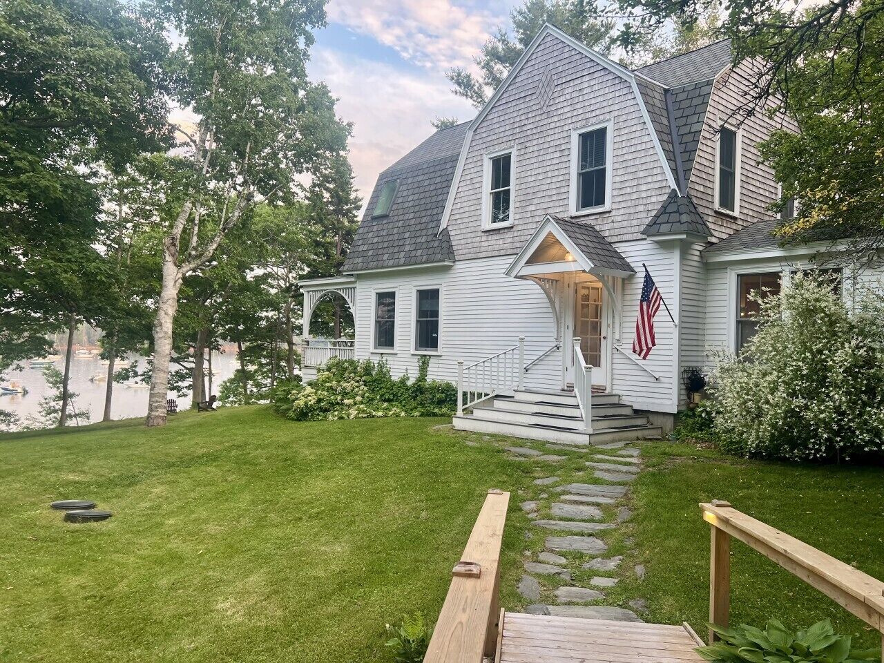 A two-story house with a front porch, a flag, and a stone pathway leading to the entrance.