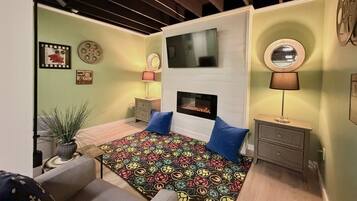 Un dormitorio con cama, televisión, chimenea y espejo.