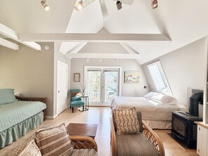 Een kamer met een hoogslaper, een bank, een stoel, een open haard en een balkon met uitzicht.