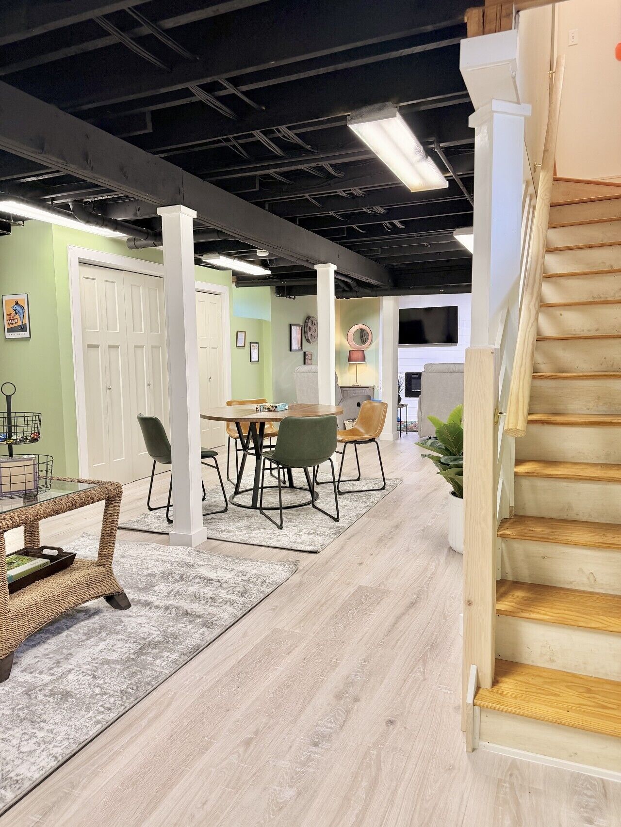 A modern interior with a dining area, staircase, and a view of the outside.