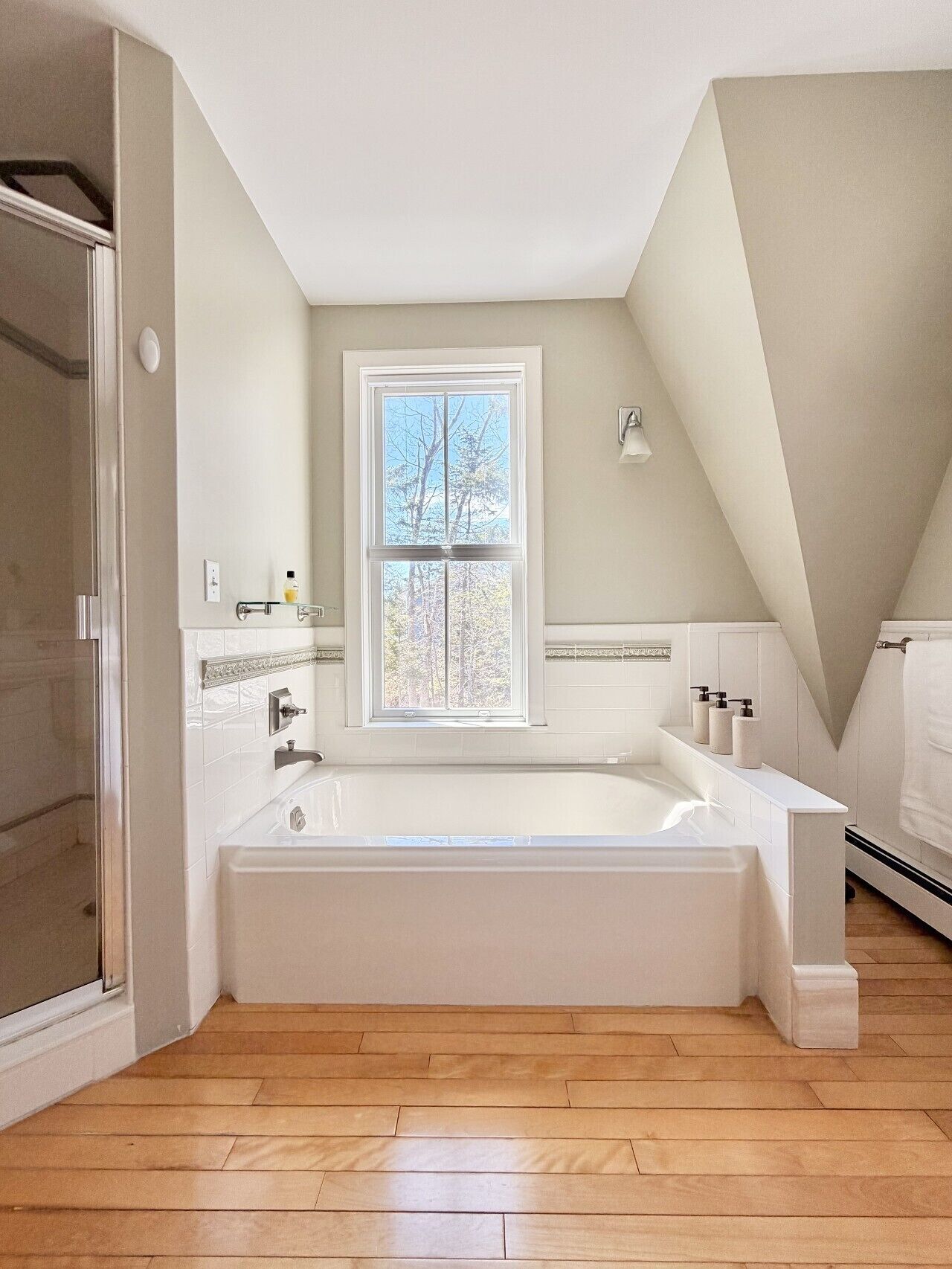 Un bagno moderno con una vasca freestanding, una finestra e uno spazio doccia.
