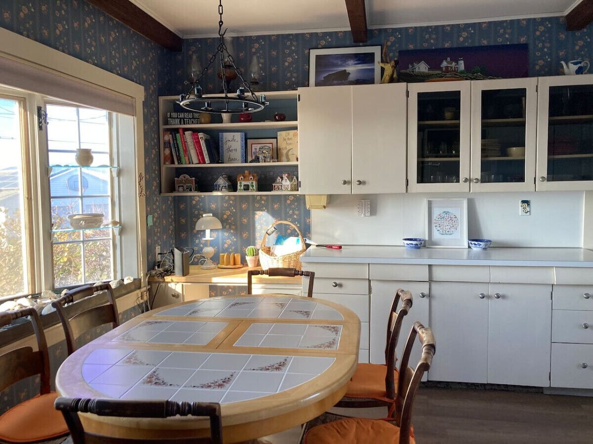 A kitchen with a round dining table, white cabinets, and a window with a view.
