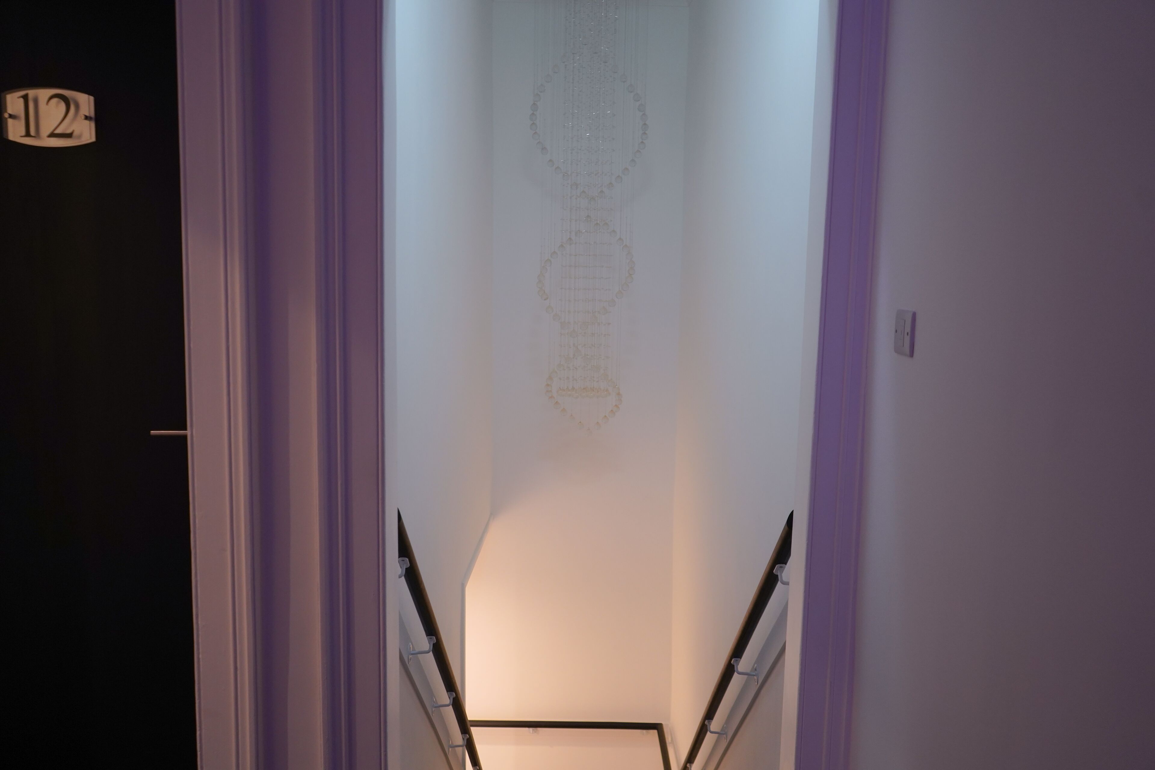 A narrow hallway with a number sign '12' on the left, leading to a staircase.
