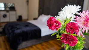Un dormitorio con una cama, una mesita de noche y un florero con flores.